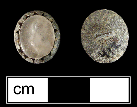 Oval-shaped sleeve link with a scalloped metal edge surrounding a colorless inset molded on the back with the pattern of a single rose. The back of this button is also decorated with a texture like a basket weave spiraling out from the center.